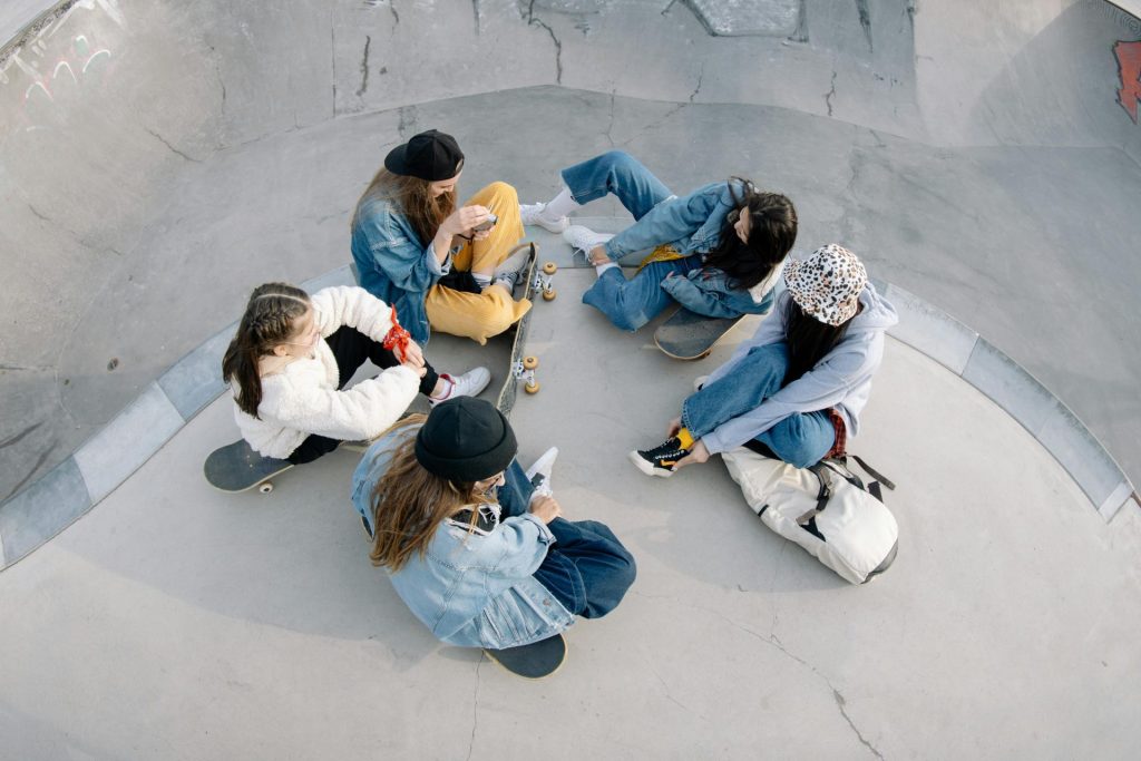 Groupe de jeunes skateurs assis et discutant dans un skatepark, photographiés d'en haut.